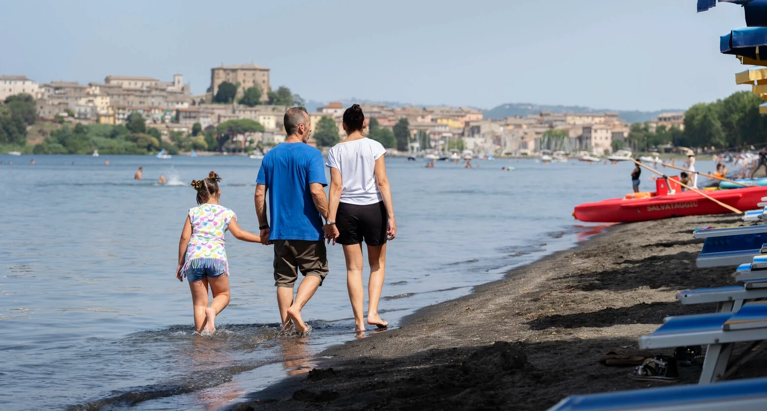 Photo of Andrea walking along a beach with his family. Andrea lives with MS and uses TAI to manage his bowel problems. 