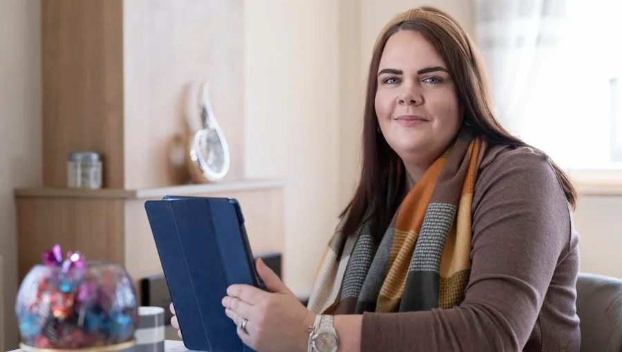 Photo of Sarah sitting at a table. It was 4 years after Sarah’s initial diagnosis that she linked her bladder issues to her MS. 